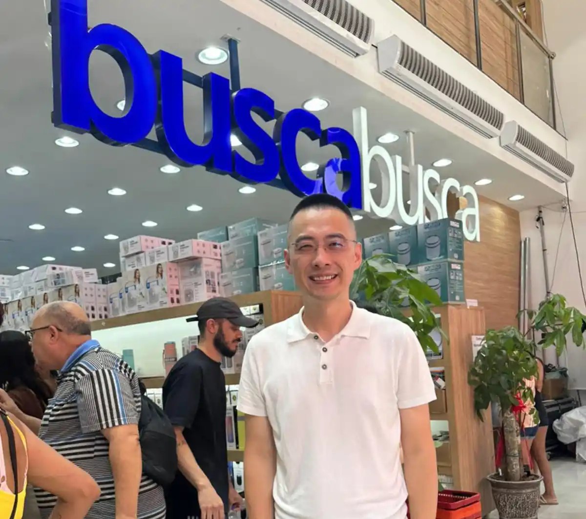 Alex Ye dentro da loja Busca Busca do Brás, embaixo do letreiro