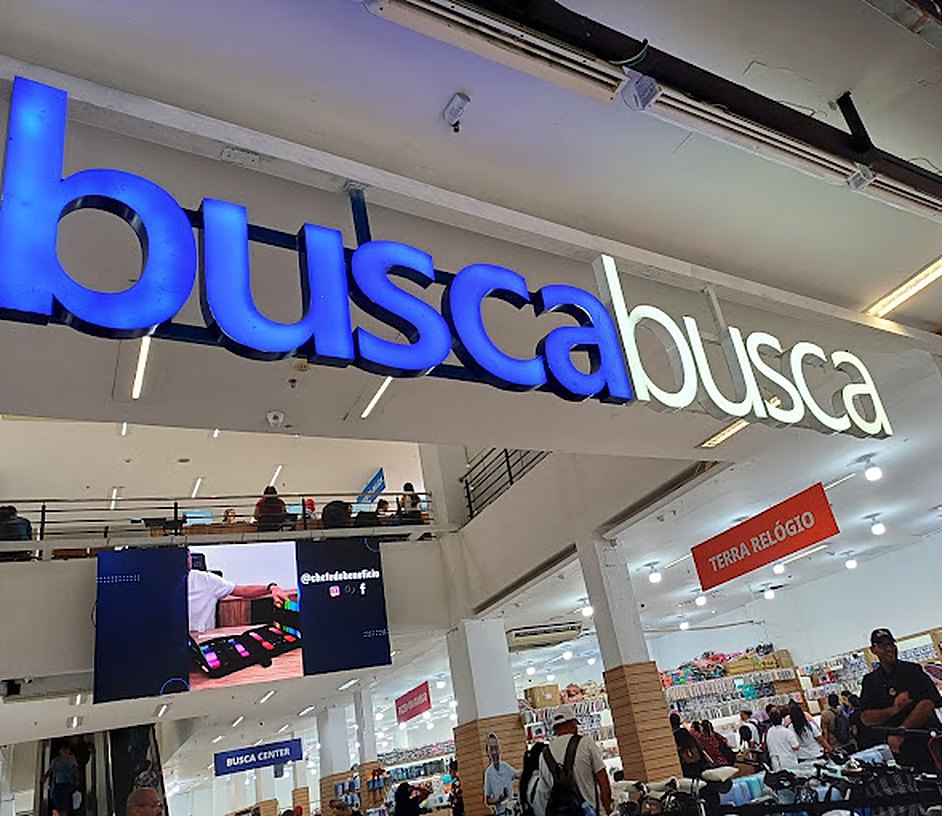 Salão interno da loja Busca Busca do Brás, com o letreiro grande e telões